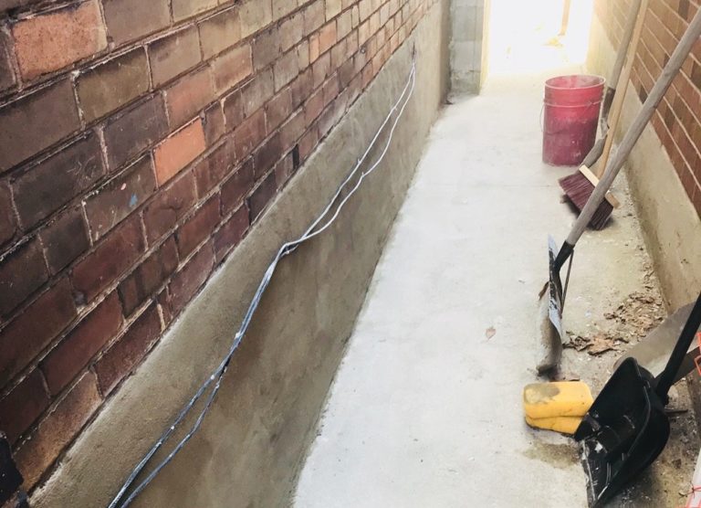 Freshly parged foundation wall beside a brick house