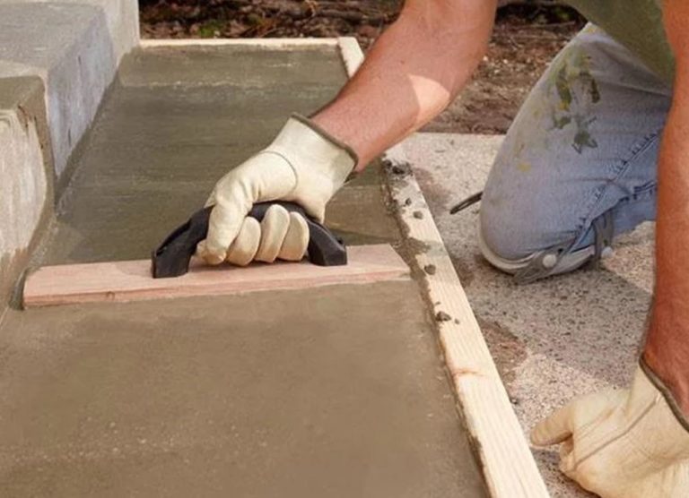 Mason finishing a new concrete step with a hand float